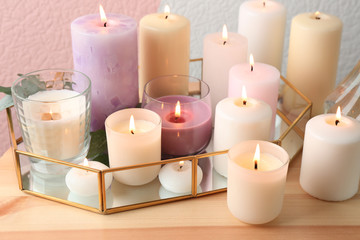 Fototapeta na wymiar Set of burning candles on table against color background