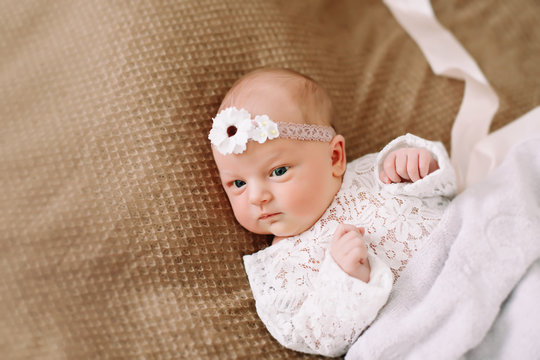 Close-up lovely newborn baby girl on a blanket. A portrait of a beautiful  newborn baby girl wearing a headband. Closeup photo