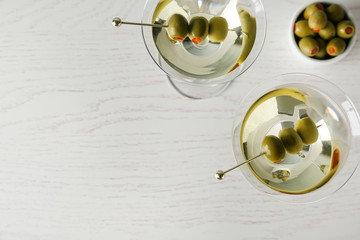 Glasses of Classic Dry Martini with olives on wooden table, flat lay. Space for text