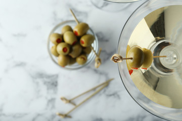 Flat lay composition with glass of Classic Dry Martini and olives on white marble table