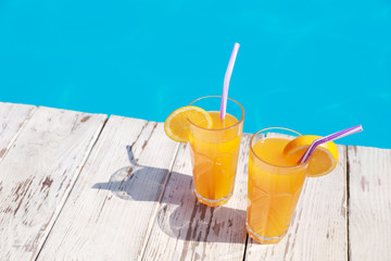 Refreshing cocktails near outdoor swimming pool on sunny day. Space for text