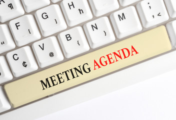 Writing note showing Meeting Agenda. Business concept for items that participants hope to accomplish at a meeting White pc keyboard with note paper above the white background