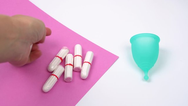 the female hand chooses the menstrual cup as an alternative to hygienic tampons, personal care products during menstruation period time close-up