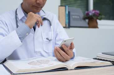 Doctor using smartphone and reading book