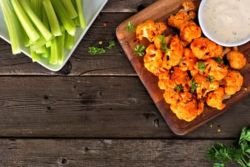 Foto auf Acrylglas Antireflex Cauliflower buffalo wings. Top view table scene against a wood background with copy space. Healthy eating, plant based meat substitute concept. © Jenifoto