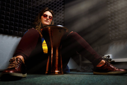 Woman sits on the floor in the recording studio and plays the ethnic drum djembe. Professional recording of African percussion instruments at the music studio.