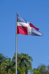 Flag of Dominican Republic (DR) waving in the wind with blue sky on background