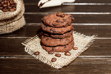Stacked chocolate chip cookies on brown wood background. Concept for a tasty snack. Sweet dessert.  Selective focus. Close up. Coffee beans.