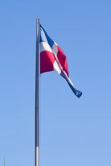 Flag of Dominican Republic (DR) waving in the wind with blue sky on background