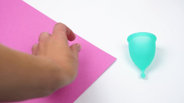the female hand chooses the menstrual cup as an alternative to hygienic tampons, personal care products during menstruation period time close-up