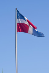 Flag of Dominican Republic (DR) waving in the wind with blue sky on background