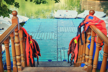 The dock with paddle boats in the pond. Entrance to the boat station with life jackets.