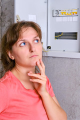 Distribution board in the house and switch off the switch. A young woman deep in thought next to...