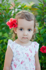 Little child girl with red flower behind her ear