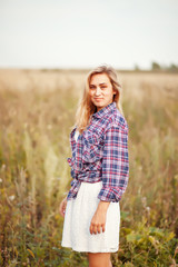 Fototapeta na wymiar Beauty young woman in checkered shirt and white dress outdoors enjoying nature. Cowgirl style.