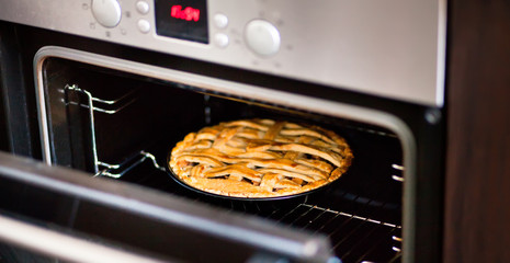 baking traditional apple pie in the oven in the kitchen