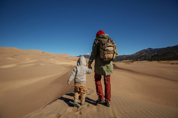 A man with his son are hiking in desert