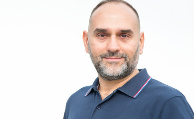 Close-up portrait of a middle-aged man looking at the camera while standing on a light background.