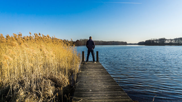 Mann auf einem Steg an einem See