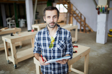 Obraz premium Waist up portrait of mature carpenter looking at camera while standing in carpentry workshop, copy space