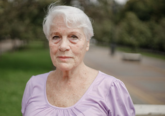 Photo portrait of an old woman in a park on a warm day