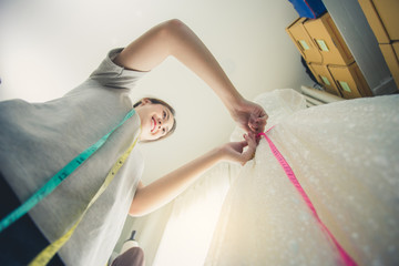 Viewed from below, young asian woman tailor measurement. Woman working with measurement tape in...