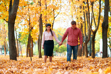 Happy couple walking in autumn city park. Bright yellow trees and leaves