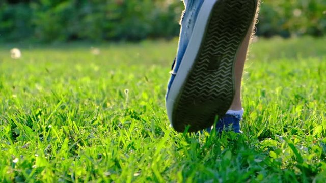 Men's legs in sneakers are walking on fresh grass, slow motion