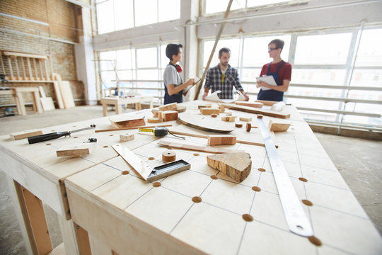 Wide angle view at group of contemporary carpenters discussing project in woodworking shop, copy space
