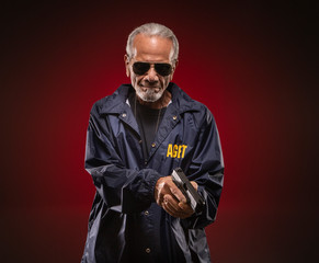 FBI Special Agent with a gun, smiling at the camera while wearing sunglasses. © Straight8Stock