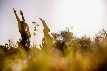 Selbstklebende Fototapeten Entspannung Four young women are practising yoga in the open air in the nature on the grass on the sunny day  © Leika production