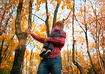 Children and father playing and having holiday in autumn city park. Posing, smiling, playing and having fun. Bright yellow trees and leaves