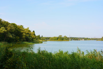 Beautiful view of the Samara River with picturesque steep banks and coast, trees, greenery and rich sky. Bright and unforgettable nature in the housing estate, Shevchenko, Dnipro, Ukraine.
