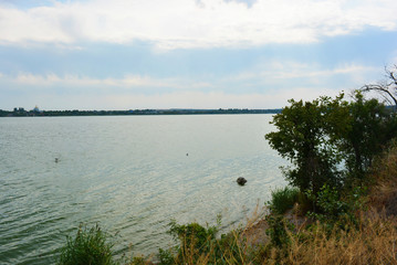 Beautiful view of the Samara River with picturesque steep banks and coast, trees, greenery and rich sky. Bright and unforgettable nature in the housing estate, Shevchenko, Dnipro, Ukraine.