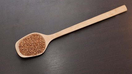 buckwheat in a wooden spoon on a wooden table