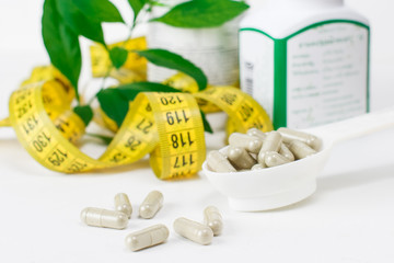 Dietary supplement tablets, measuring tape. Close-up