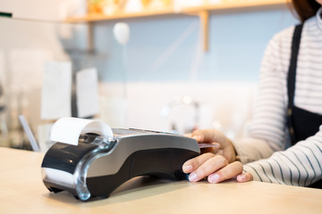 Customer using credit cart for payment to owner at cafe restaurant, cashless technology and credit card payment concept