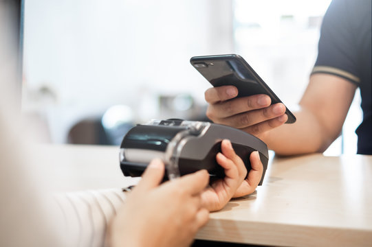 Customer using phone for payment to owner at cafe restaurant, cashless technology and credit card payment concept - Powered by Adobe