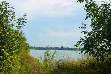 Fototapeta na wymiar Beautiful view of the Samara River with picturesque steep banks and coast, trees, greenery and rich sky. Bright and unforgettable nature in the housing estate, Shevchenko, Dnipro, Ukraine.
