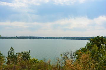 Beautiful view of the Samara River with picturesque steep banks and coast, trees, greenery and rich sky. Bright and unforgettable nature in the housing estate, Shevchenko, Dnipro, Ukraine.