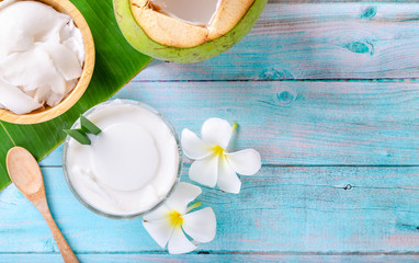 Young coconut pudding served in a glass cup decorated with coconut meat looks delicious on the banana leaves and a beautiful blue wooden table.