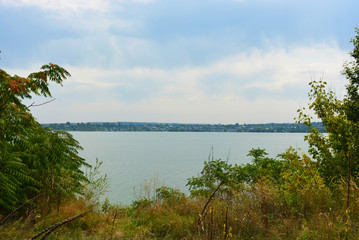 Beautiful view of the Samara River with picturesque steep banks and coast, trees, greenery and rich sky. Bright and unforgettable nature in the housing estate, Shevchenko, Dnipro, Ukraine.