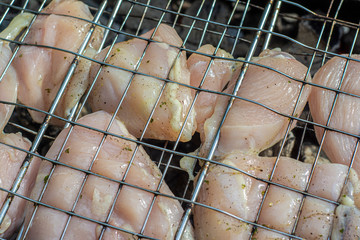 Raw chicken meat on the grill before cooking on a barbecue over the coals