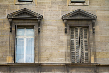Close-up of traditional windows with porticoes and shutters on the facade of a building in the historical center of Paris