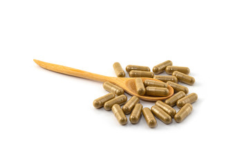 Herb capsules with spoon isolated on white background