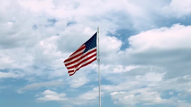 american flag waving in the wind against blue sky slow motion