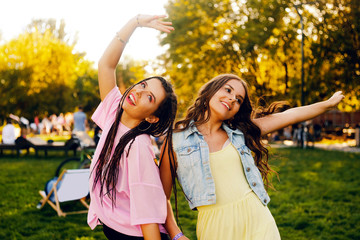 Portrait of a two brunette in a park at a festival. A two sister friends in pink dance.  Girls...