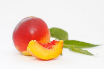 Delicious and juicy nectarina peach with leaves on white background. Healthy summer fruit.