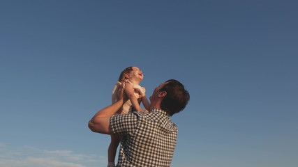 Dad throws up a happy daughter in the blue sky. Father and little child play, laugh and hug together. Happy family travels. Baby in the arms of the parent. Dad day off. The concept of a happy family