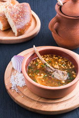 Homemade Lamb Soup Piti or Putuk with Cherry Plums in Vintage Ceramic Bowl on Rustic Background. Azerbaijani Bozbash with Mutton, Vegetables and Spices or Clear Sturdy Seasoned Broth Close Up